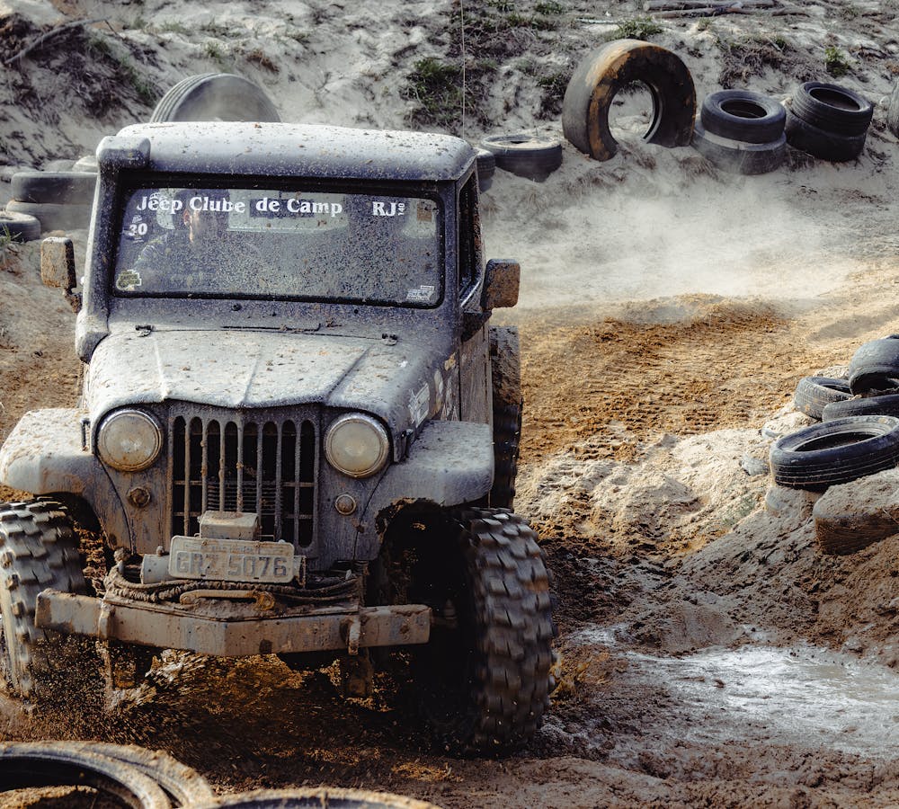 RECON TRAIL Off-Road Tires in Mud Terrain Off-road Jeep driving through muddy terrain equipped with rugged RECON TRAIL off-road tires.
